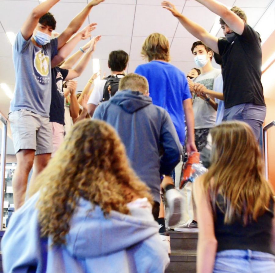 Upper School students participating in a long-standing tradition: freshmen walk through a bridge of seniors that spans from the auditorium to the gym