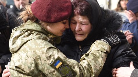 A Ukrainian soldier in uniform supports a fellow citizen in times of need.