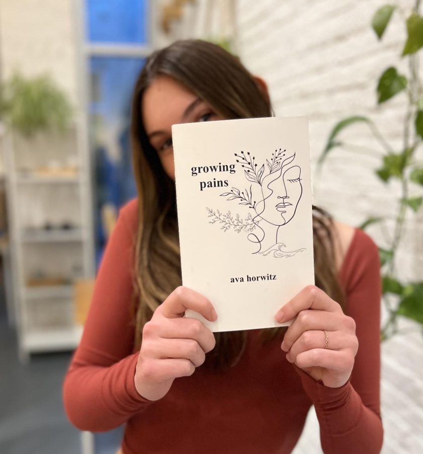 Junior Ava Horwitz holding her debut book, Growing Pains, a poetry collection.