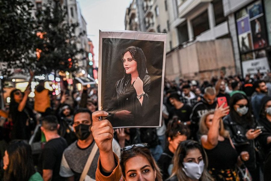 A protester in Iran holds a photo of Mahsa Amini.