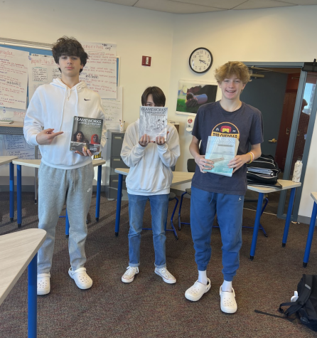 Freshmen Marc Abrahams, Connor Kernan, and Flynn Ogden stand with their copies of Frameworks of World History.