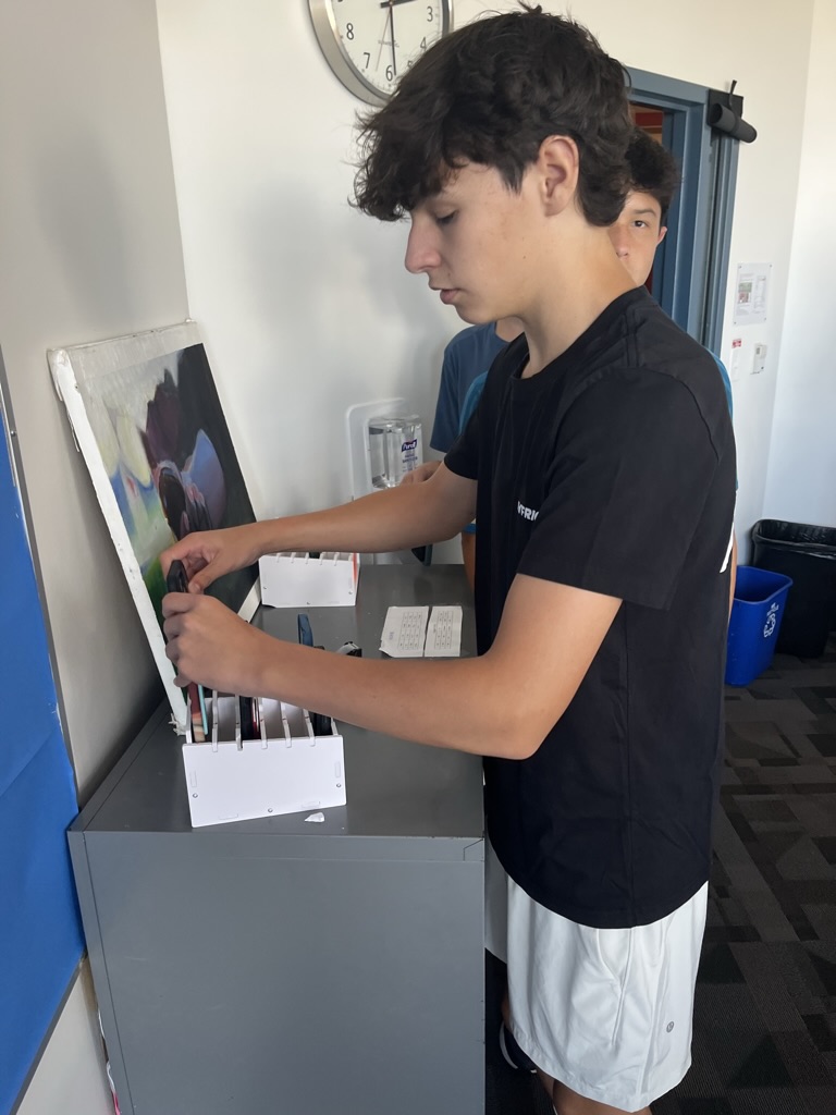 Sophomore Jordi Lopez places his phone in his assigned slot, where it will remain for the duration of the class.