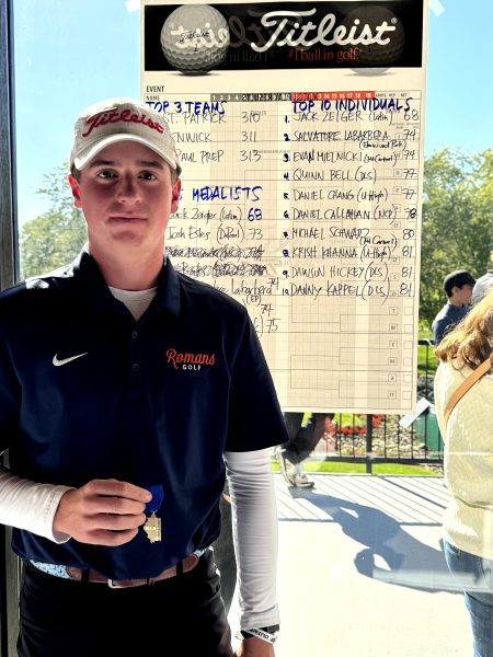 Junior Jack Zeiger, holding his first place medal, next to the scoreboard at Regionals.