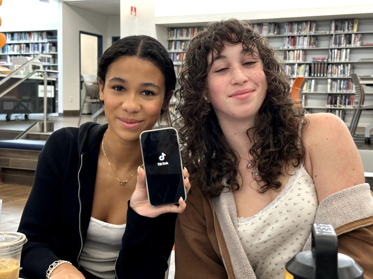 Juniors Isabella Hudson and Roxie Lara hold up a phone while on TikTok.