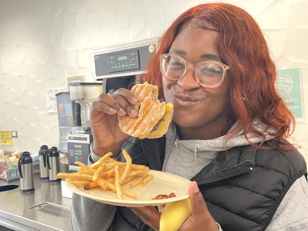 Senior Mel Butler takes a bite of the Donut Bacon Cheeseburger.