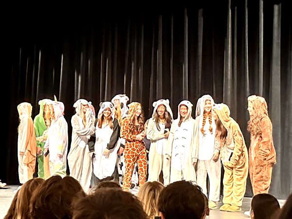 The varsity girls field hockey team parades their onesies onstage.