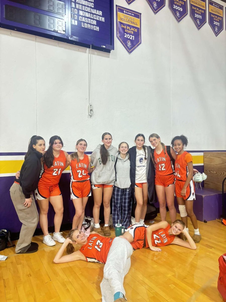 Girls varsity basketball players pose after a win.