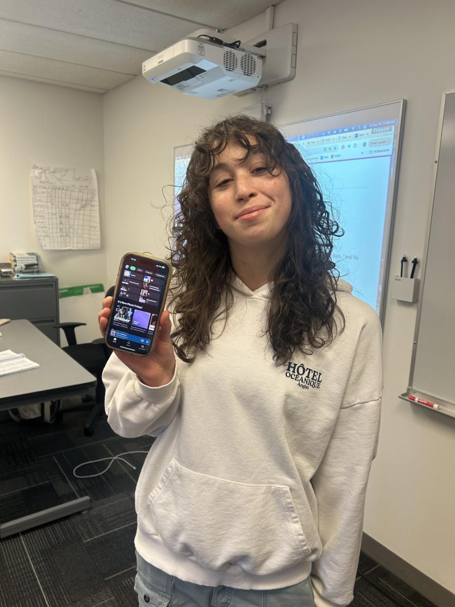 Junior Roxie Lara holds up her phone with Spotify opened