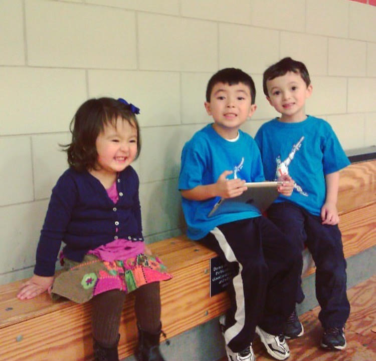 Harper, Gavin, and Grayson Anderson watching their mom's team's basketball game.