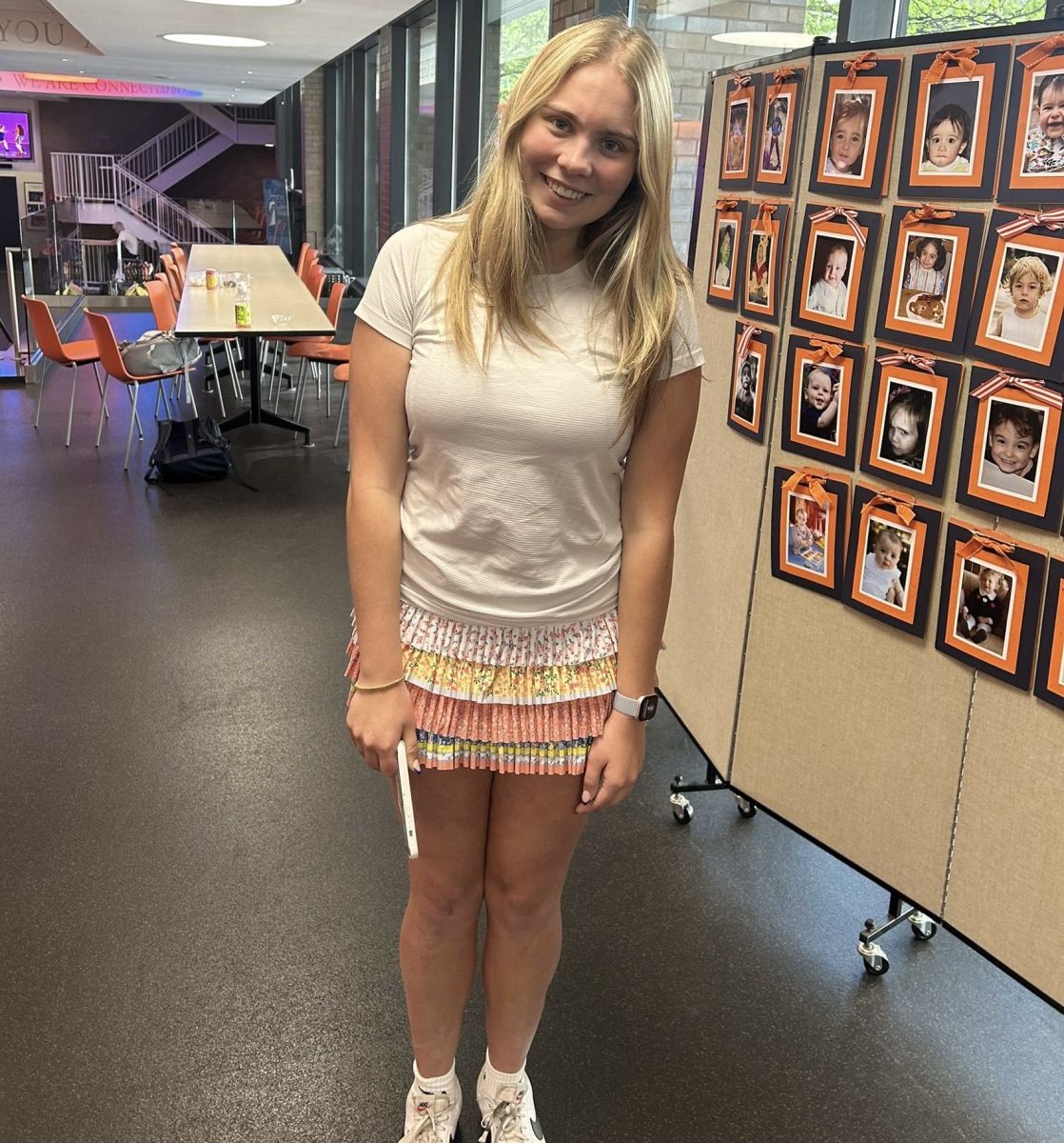 Senior Reilly Henderson poses in front of the Class of 2025 Then & Now Board.