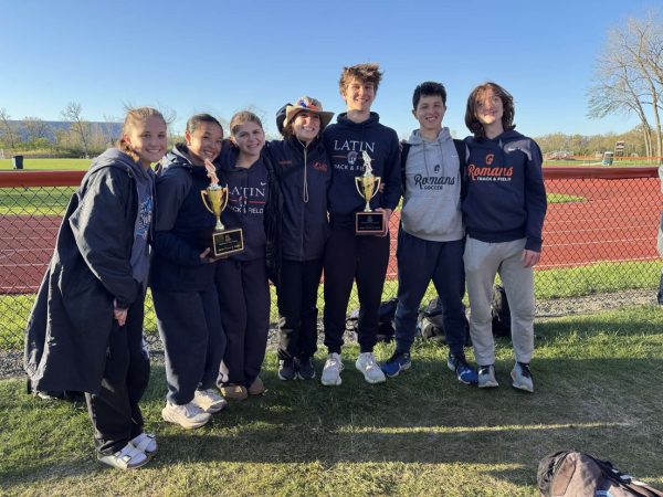 Track and field athletes pose with trophies. 