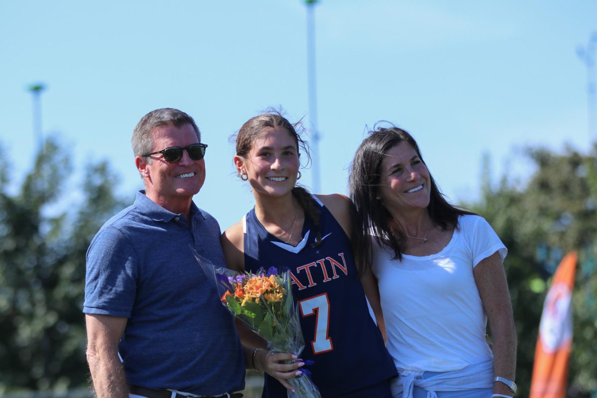 Teagan Moroney celebrates her senior recognition with her parents after defeating Parker at Latin's Homecoming.