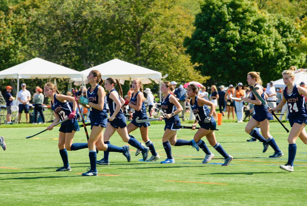 The varsity field hockey team runs onto the field.
