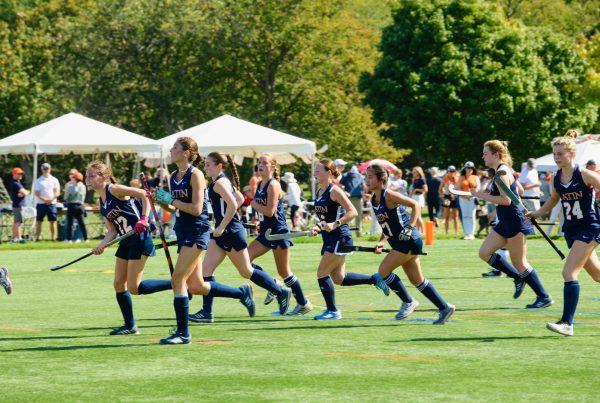 The varsity field hockey team runs onto the field.