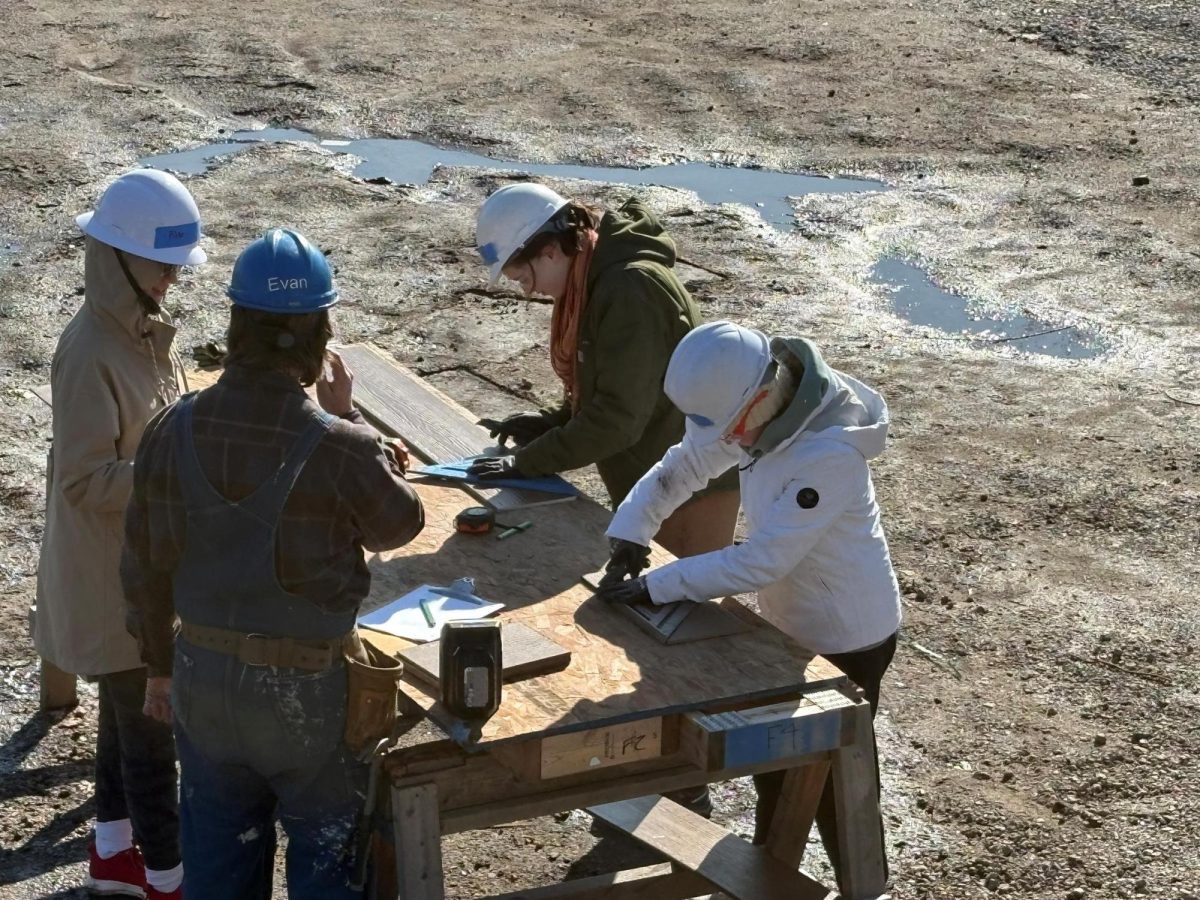 Students measure and cut wood with the help of Habitat for Humanity staff.