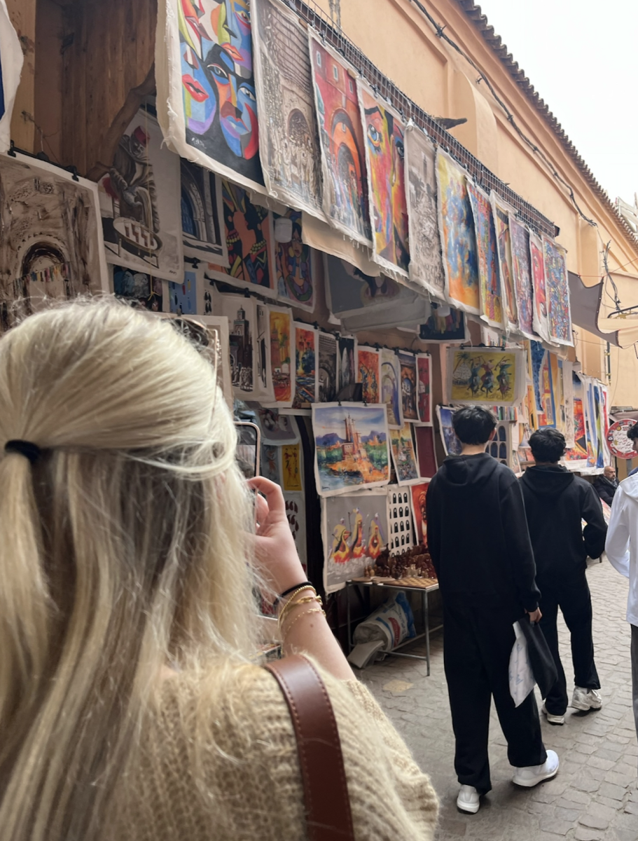 A photo of Lily Dumas taking a photo of artwork in a market in Marrakesh.
