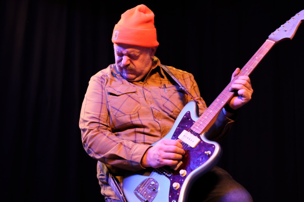 Ian Merritt playing B-flat on his electric guitar.