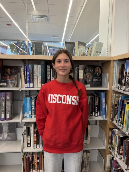 Senior Teagan Moroney stands by the books in the Learning Commons.